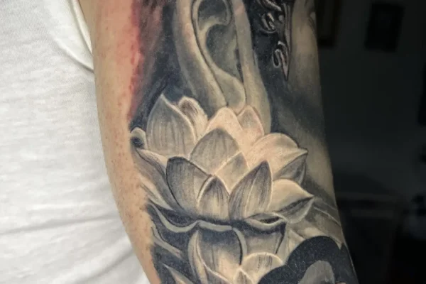 Tatuaje realista de Buddha y flor de loto con humo (estilo superrealista) en el brazo