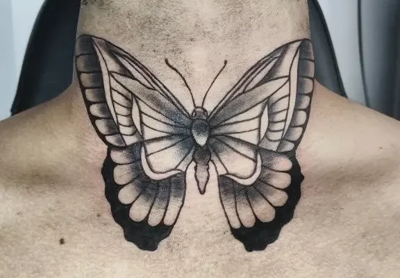 Tatuaje en el cuello frontal de mariposa estilo blackwork realista hecho en Málaga